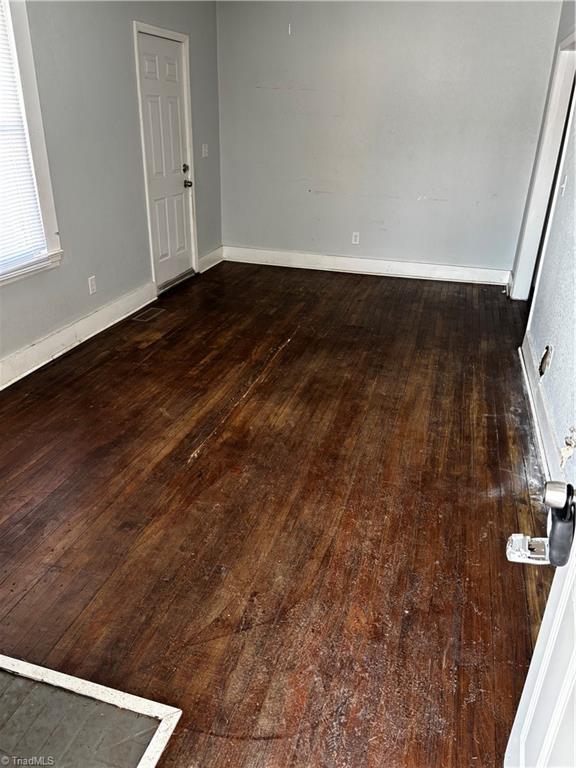 unfurnished room with dark hardwood / wood-style flooring