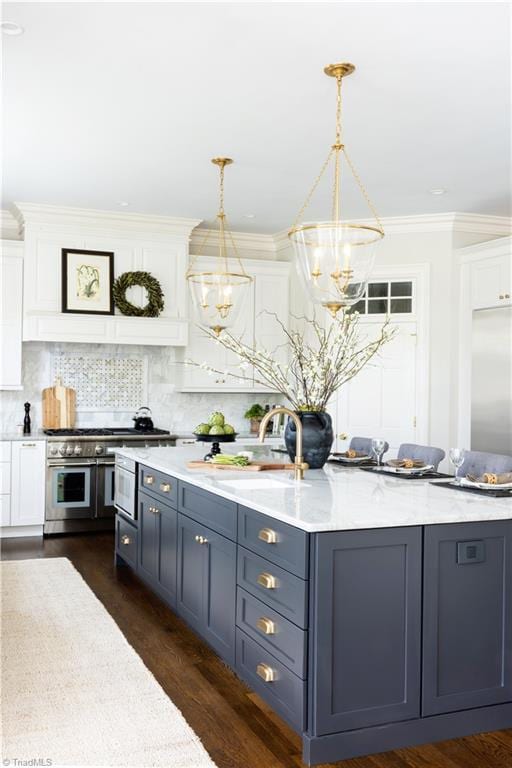 kitchen with a notable chandelier, a sink, double oven range, white cabinetry, and decorative backsplash
