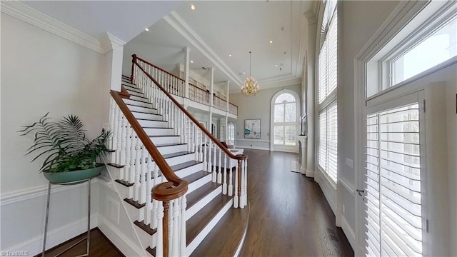 stairway featuring a notable chandelier, visible vents, crown molding, and wood finished floors