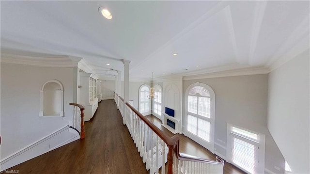 corridor featuring decorative columns, ornamental molding, wood finished floors, a baseboard heating unit, and an upstairs landing