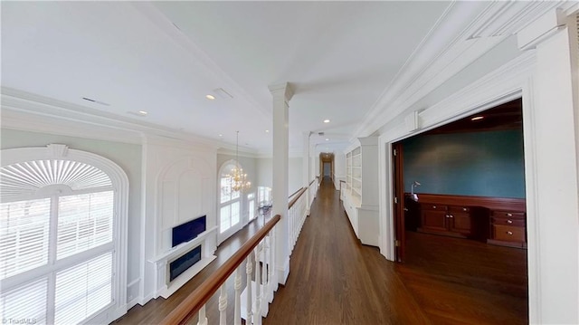 hall with crown molding, an upstairs landing, a chandelier, and dark wood-style flooring