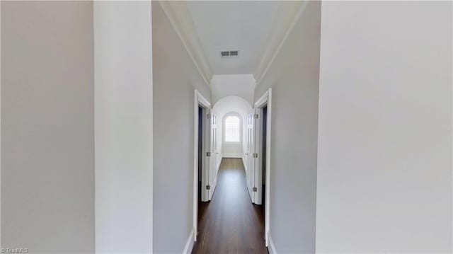hallway featuring baseboards, dark wood-style floors, visible vents, and ornamental molding