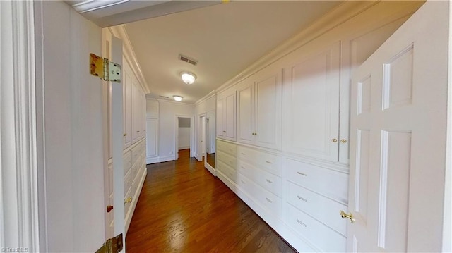 hallway featuring dark wood-style flooring, ornamental molding, and visible vents