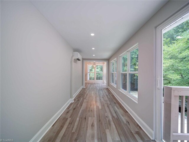 corridor with a wall mounted AC and light hardwood / wood-style flooring