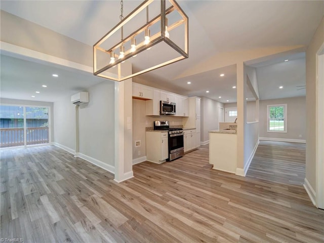 kitchen featuring a wall mounted air conditioner, stainless steel appliances, white cabinets, sink, and light hardwood / wood-style flooring