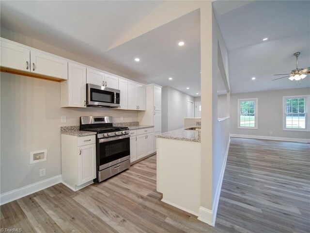 kitchen featuring appliances with stainless steel finishes, light hardwood / wood-style flooring, white cabinetry, and vaulted ceiling