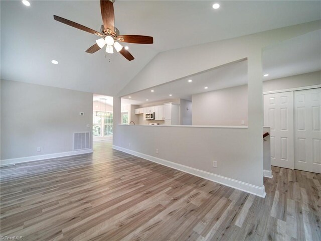 unfurnished living room with high vaulted ceiling, light wood-type flooring, and ceiling fan