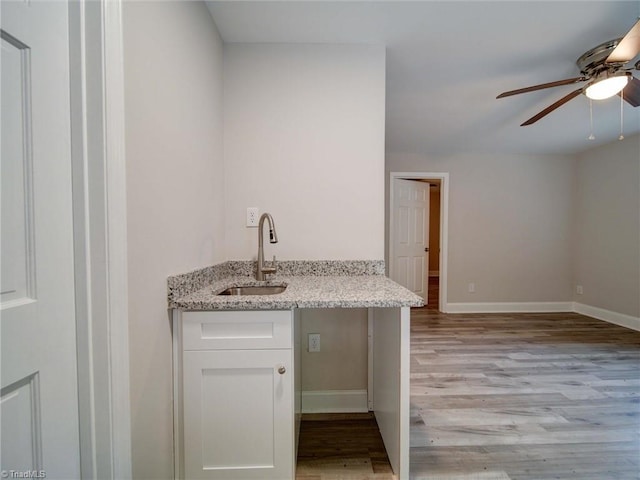 interior space with ceiling fan, white cabinets, light wood-type flooring, sink, and light stone countertops