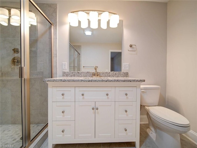 bathroom with a shower with shower door, vanity, tile patterned floors, and toilet