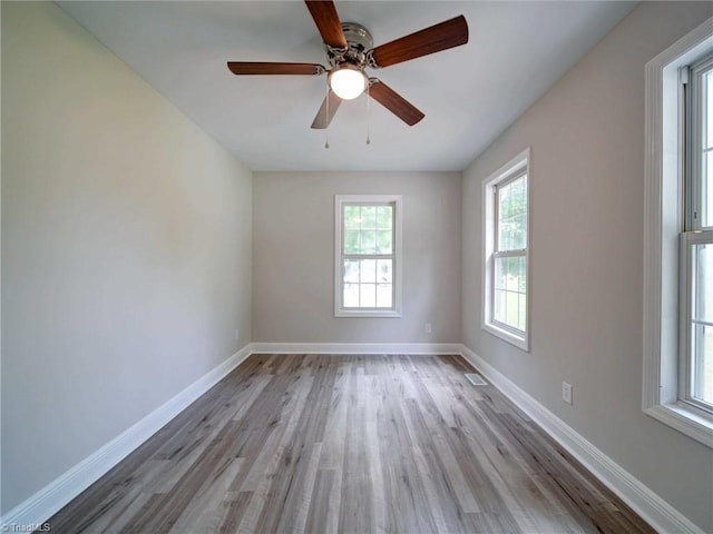 spare room with a wealth of natural light, ceiling fan, and light wood-type flooring