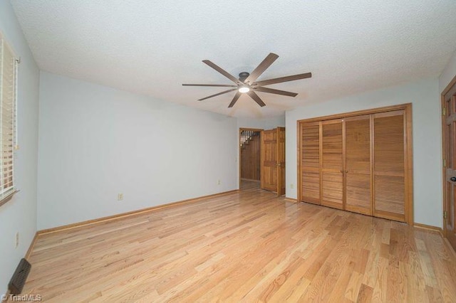 unfurnished bedroom with light wood-style floors, a closet, baseboards, a textured ceiling, and ceiling fan