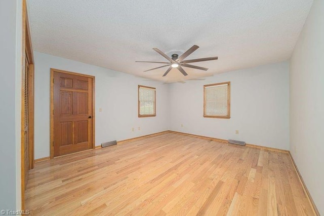 unfurnished room with light wood-style flooring, ceiling fan, a textured ceiling, and baseboards