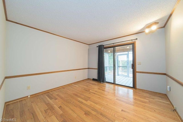 spare room featuring ornamental molding, light wood-style floors, a textured ceiling, and baseboards