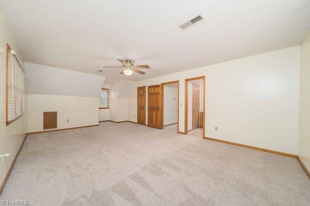 additional living space with light carpet, baseboards, a ceiling fan, and a textured ceiling