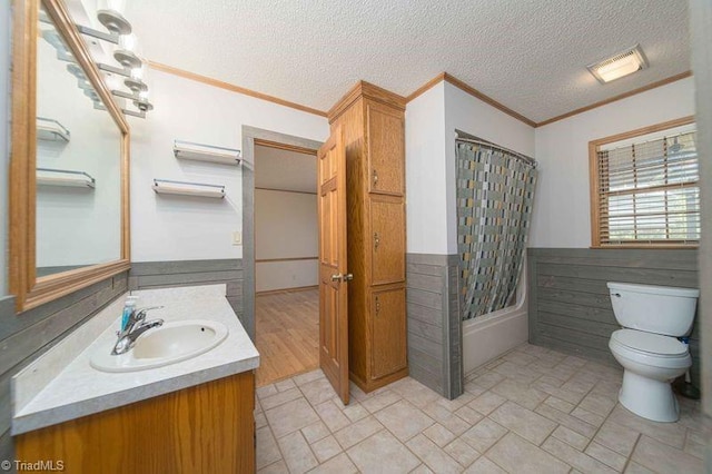 bathroom featuring ornamental molding, toilet, vanity, shower / bath combination with curtain, and a textured ceiling