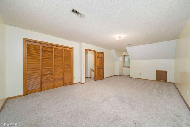 additional living space featuring carpet floors, a textured ceiling, lofted ceiling, and baseboards