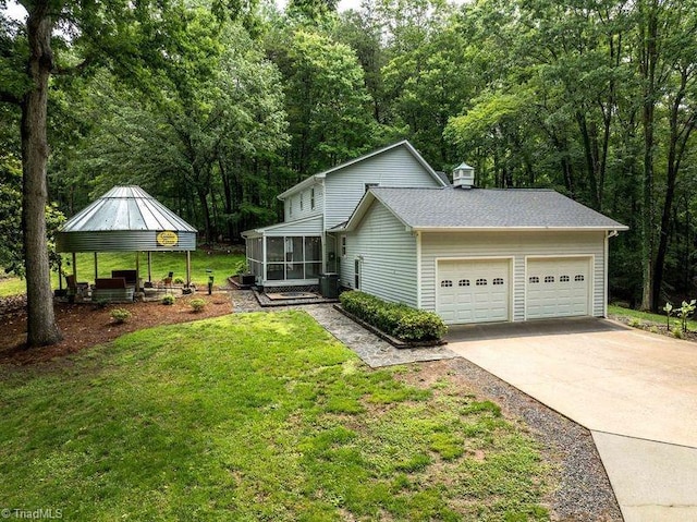 view of side of property with a sunroom, a gazebo, a garage, a yard, and driveway