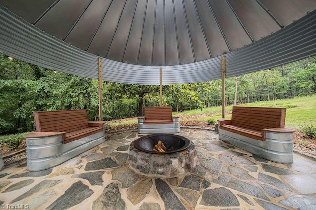 view of patio featuring an outdoor fire pit and a view of trees