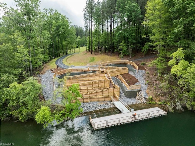 view of property's community with a floating dock, a water view, and a wooded view