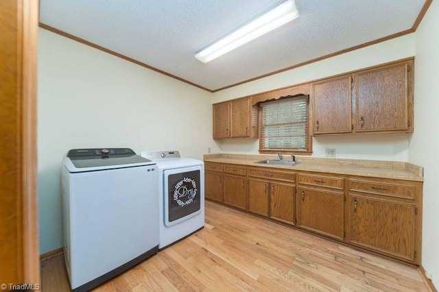 clothes washing area with crown molding, cabinet space, washer and dryer, and light wood-style flooring