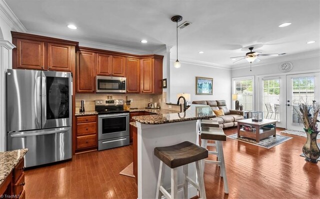 3615 Sainsbury Ln, Greensboro, NC 27409 - kitchen featuring stainless steel appliances, a peninsula, crown molding, a ceiling fan, and a kitchen breakfast bar