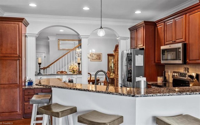 3615 Sainsbury Ln, Greensboro, NC 27409 - kitchen featuring appliances with stainless steel finishes, ornate columns, arched walkways, dark stone counters, and a breakfast bar