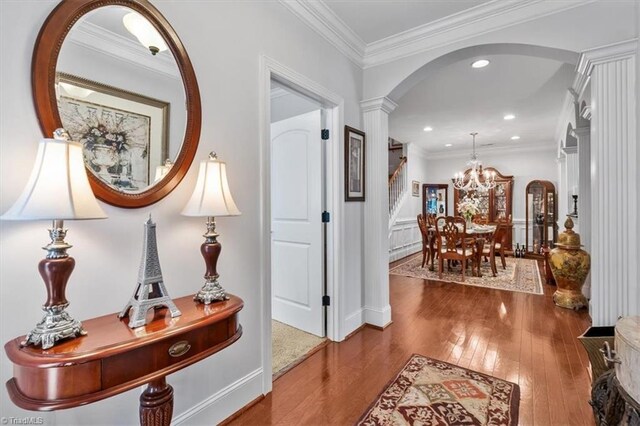 3615 Sainsbury Ln, Greensboro, NC 27409 - hallway with decorative columns, wood-type flooring, a chandelier, arched walkways, and stairs