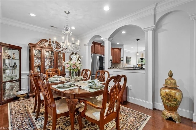 3615 Sainsbury Ln, Greensboro, NC 27409 - dining room featuring ornate columns, arched walkways, dark wood-style floors, recessed lighting, and a chandelier