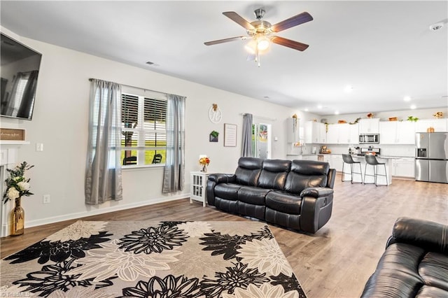 living area with recessed lighting, a ceiling fan, light wood finished floors, and baseboards