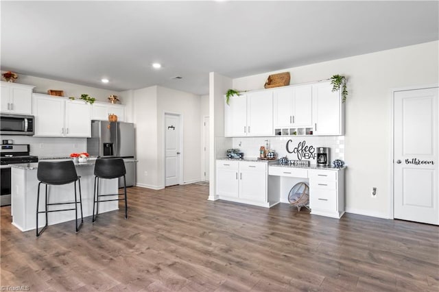 kitchen featuring a kitchen bar, appliances with stainless steel finishes, tasteful backsplash, a center island, and recessed lighting