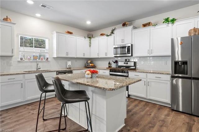 kitchen featuring decorative backsplash, a kitchen island, appliances with stainless steel finishes, a sink, and white cabinetry