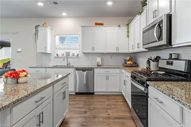 kitchen featuring visible vents, dark wood-type flooring, white cabinets, a sink, and appliances with stainless steel finishes