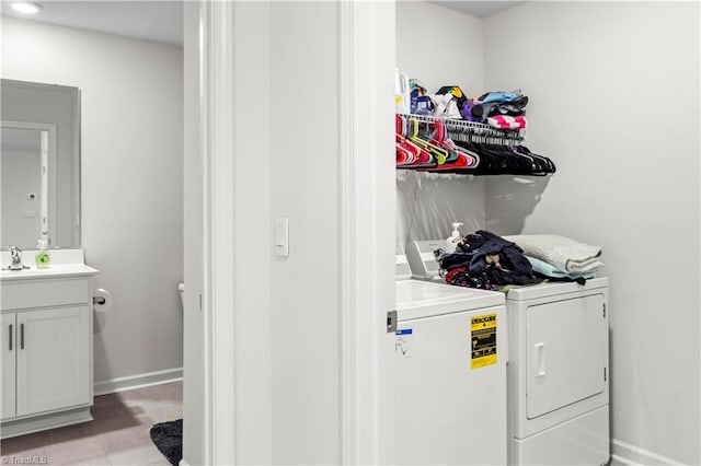 laundry area featuring laundry area, independent washer and dryer, a sink, baseboards, and light wood-style floors