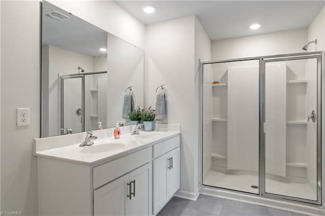 full bath featuring a sink, a shower stall, double vanity, and visible vents