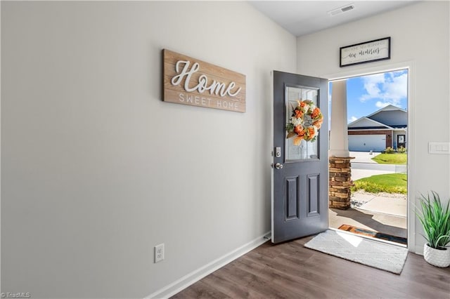 foyer entrance featuring baseboards, visible vents, and wood finished floors