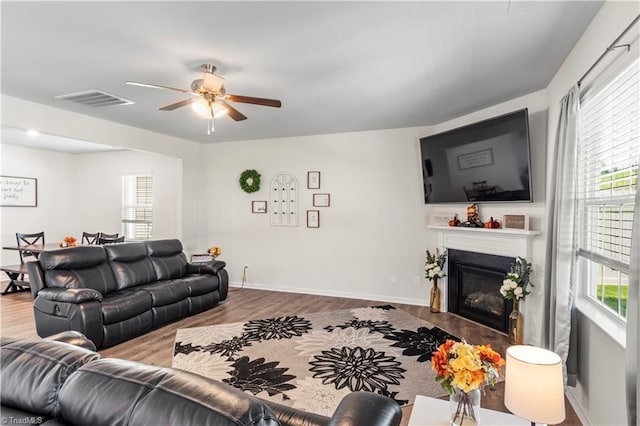 living area with visible vents, ceiling fan, wood finished floors, and a healthy amount of sunlight