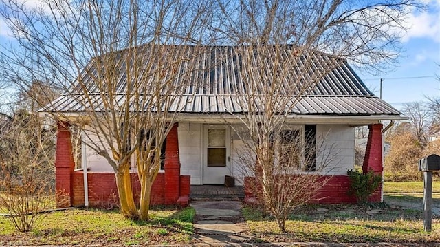 view of front of home featuring covered porch, metal roof, and brick siding