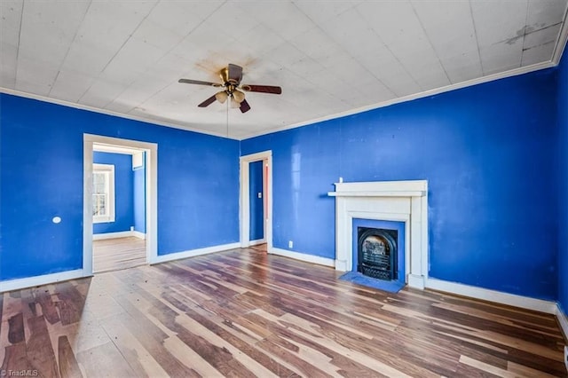 unfurnished living room featuring crown molding, baseboards, wood finished floors, and a fireplace with flush hearth