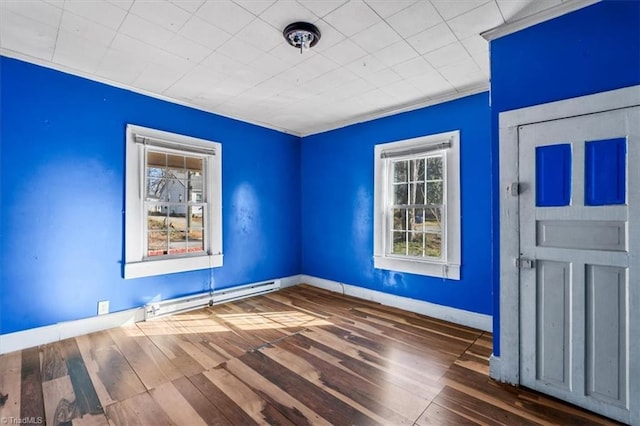 empty room with crown molding, baseboards, baseboard heating, and hardwood / wood-style floors