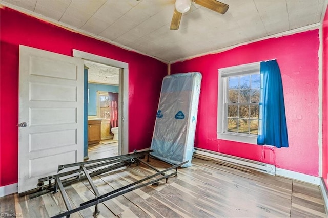 interior space featuring a ceiling fan, a baseboard radiator, baseboards, and wood finished floors