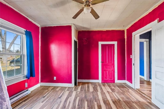 spare room featuring baseboards, a ceiling fan, a baseboard radiator, wood finished floors, and crown molding