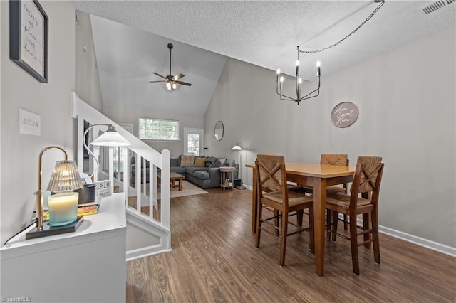 dining room featuring wood finished floors, a chandelier, ceiling fan, a textured ceiling, and high vaulted ceiling