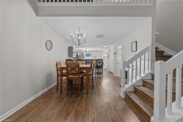 dining area with wood finished floors, stairway, a chandelier, baseboards, and a textured ceiling