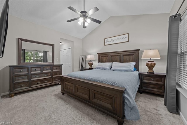 bedroom featuring light carpet, lofted ceiling, ceiling fan, a closet, and baseboards