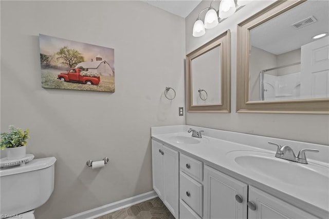 full bathroom featuring toilet, baseboards, double vanity, and a shower