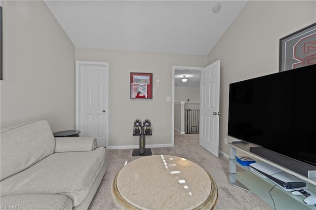 carpeted living area with baseboards and vaulted ceiling