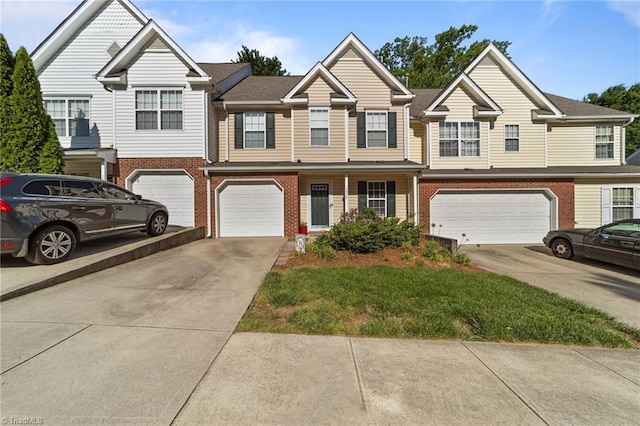 townhome / multi-family property featuring a garage, brick siding, and driveway