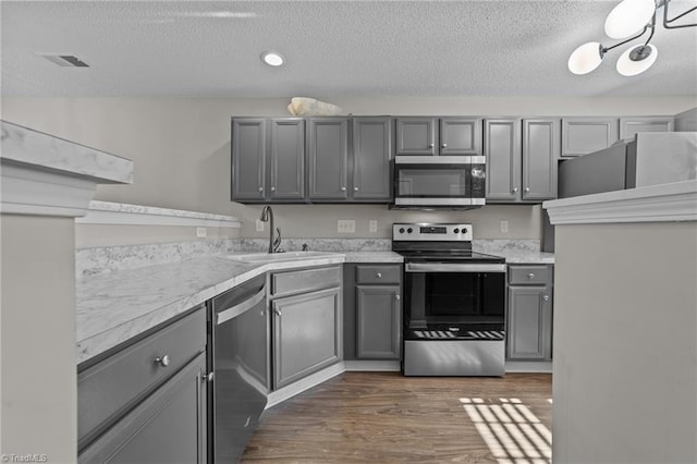 kitchen with stainless steel appliances, a sink, gray cabinets, a textured ceiling, and light countertops
