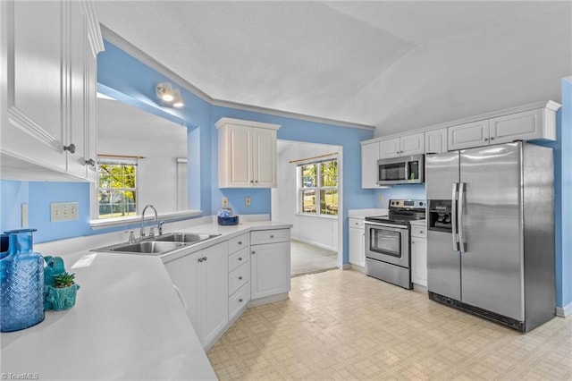 kitchen with white cabinets, sink, lofted ceiling, and stainless steel appliances