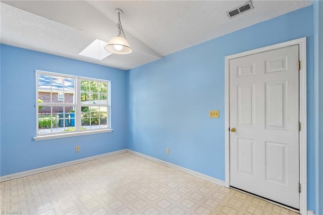 empty room with lofted ceiling with skylight and a textured ceiling